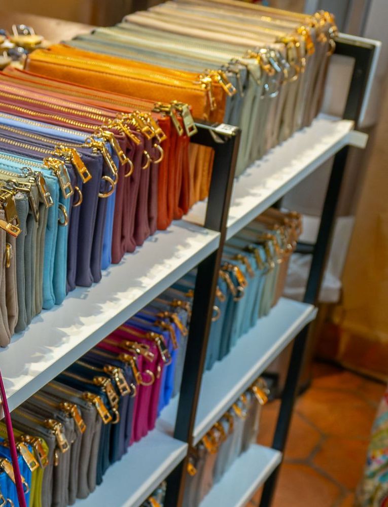 A shelf of crossbody bags in every color, lined up with gold zippers