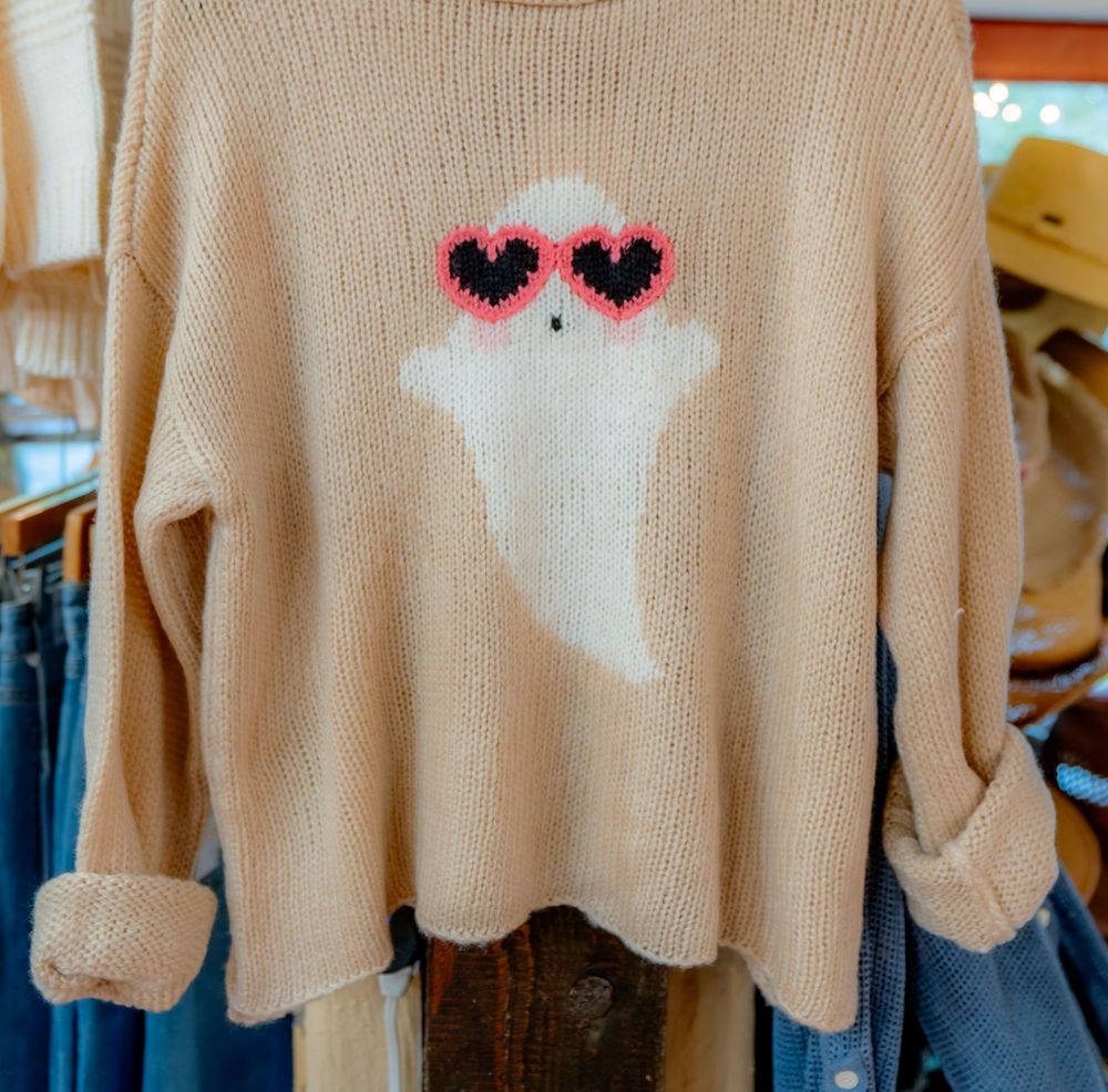 A peach knit sweater with a white ghost wearing pink heart-shaped sunglasses