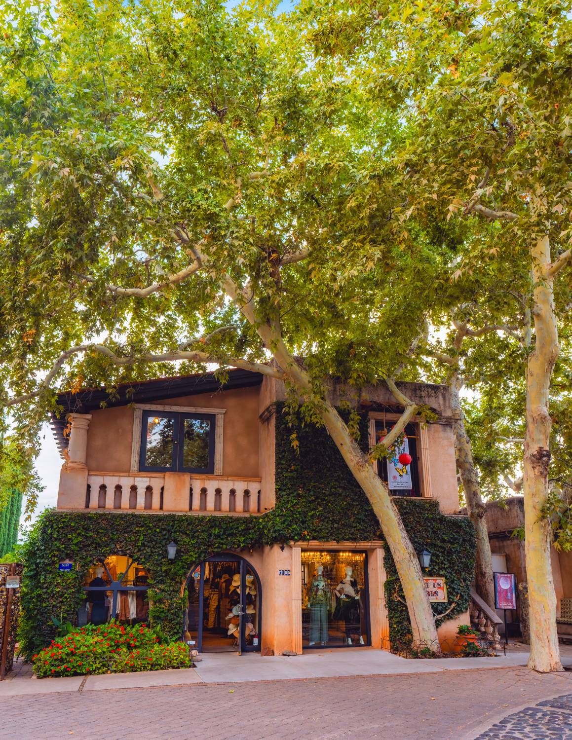 The Just Us Girls building under tall sycamore trees in Tlaquepaque Village